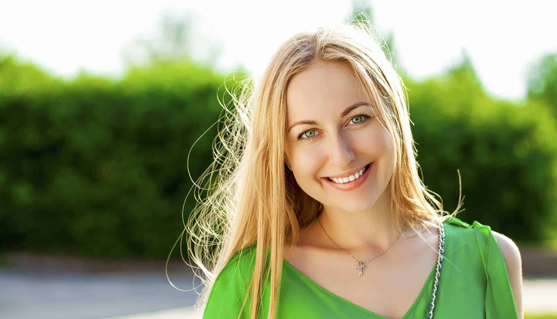 Close up Portrait, Young beautiful blonde woman in green dress posing outdoors in sunny weather