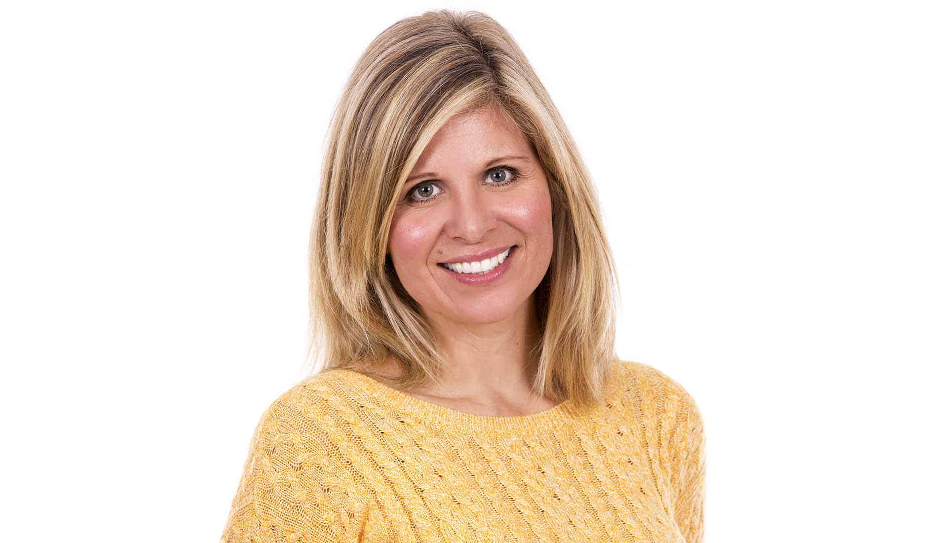 Blonde woman in yellow jumper smilling. Porelain veneers Atlanta, GA.